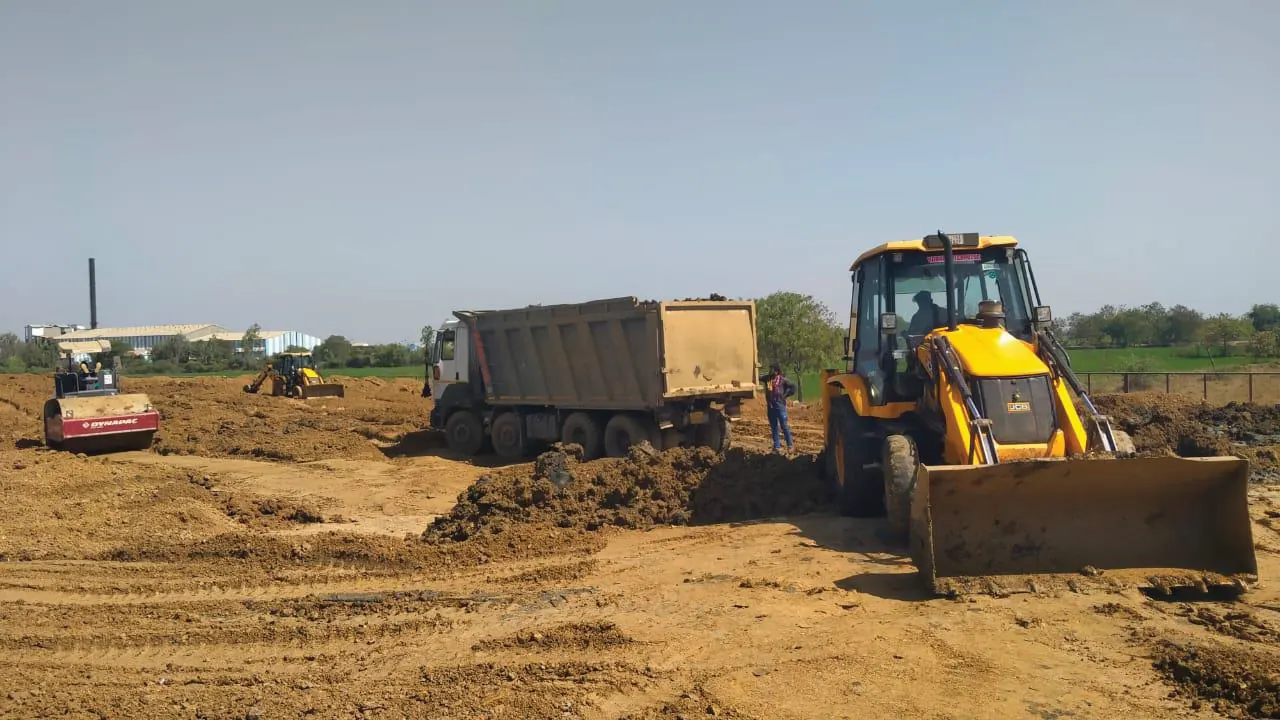 Backhoe loader and compactor at active worksite